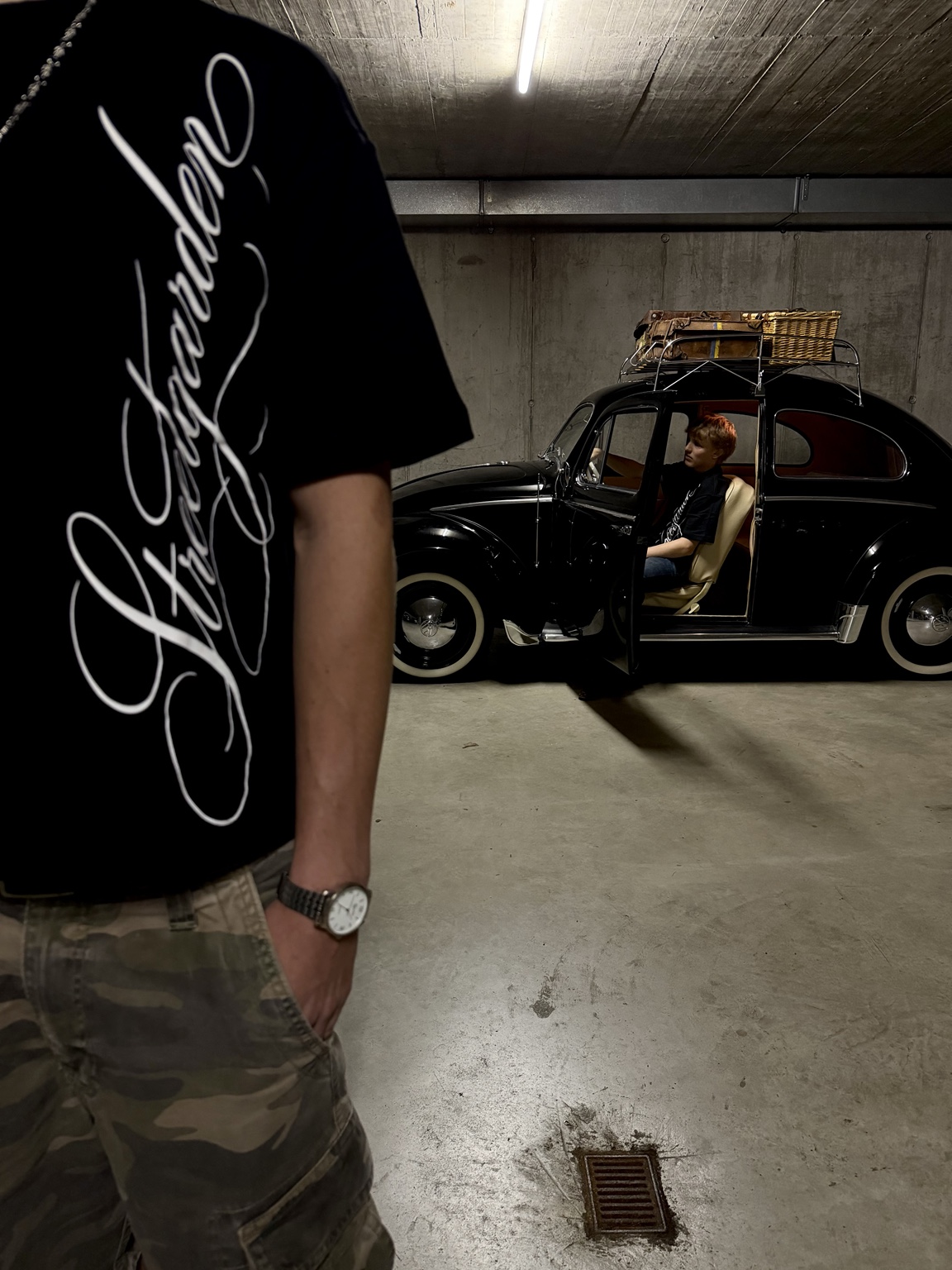 T-Shirt im Vordergrund und Person im Oldtimer